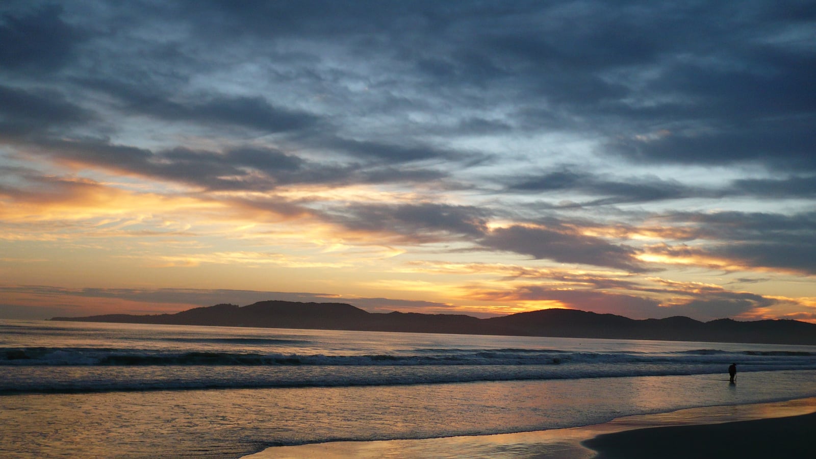 Vista aérea da orla verticalizada de Itapema ao entardecer, com a praia extensa e as torres à beira-mar